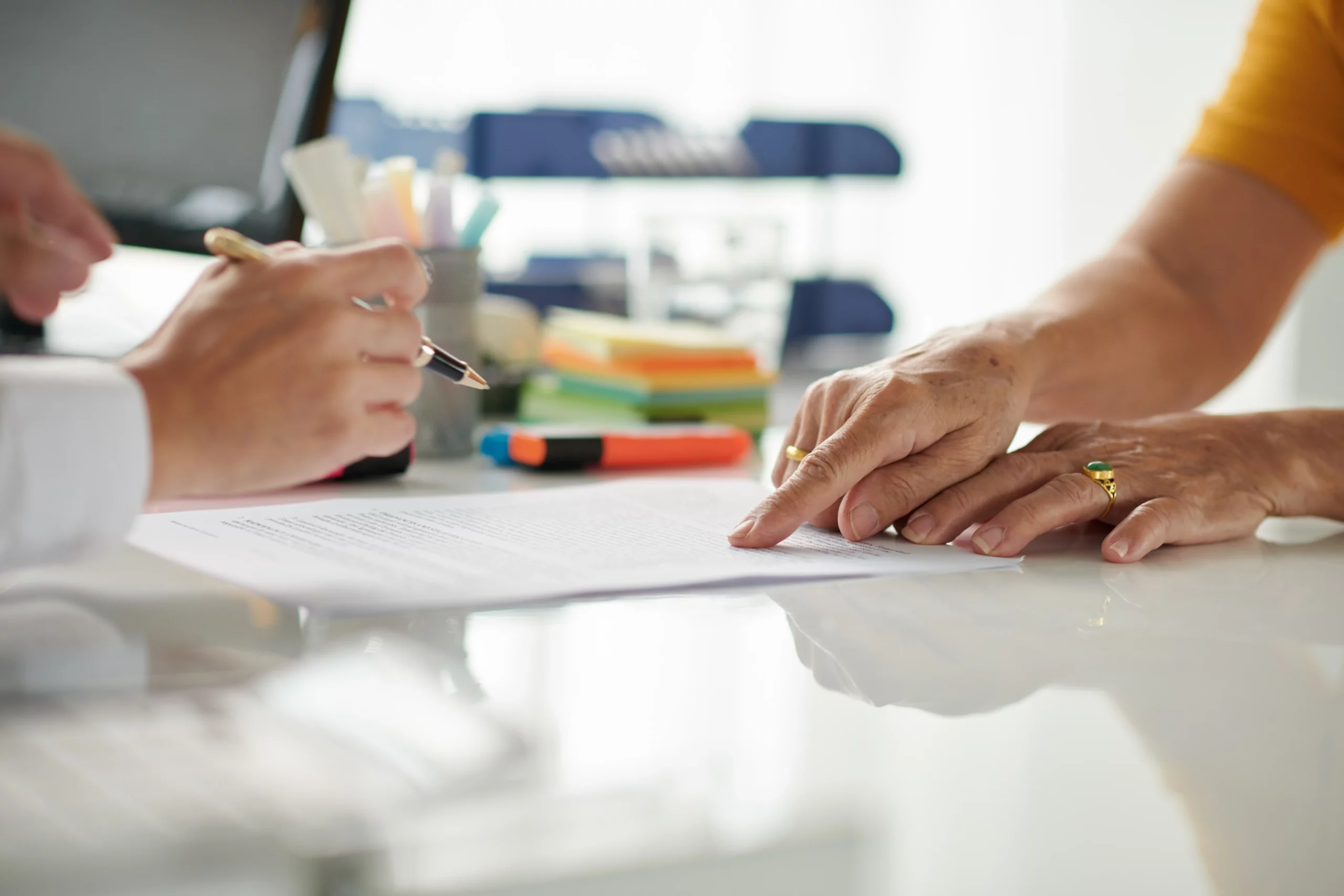 Close-up of hands reviewing and pointing at legal documents on a desk, symbolizing estate planning and Power of Attorney discussions.