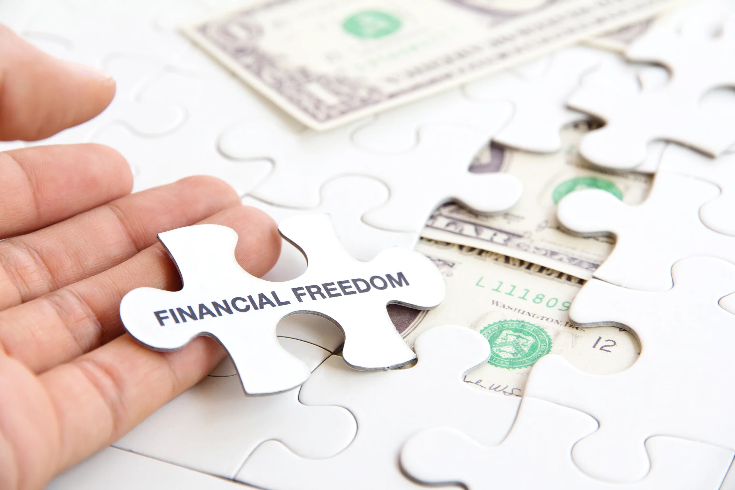 Hand holding a puzzle piece labeled “Financial Freedom” above scattered U.S. dollar bills, symbolizing debt relief through bankruptcy in Missouri.