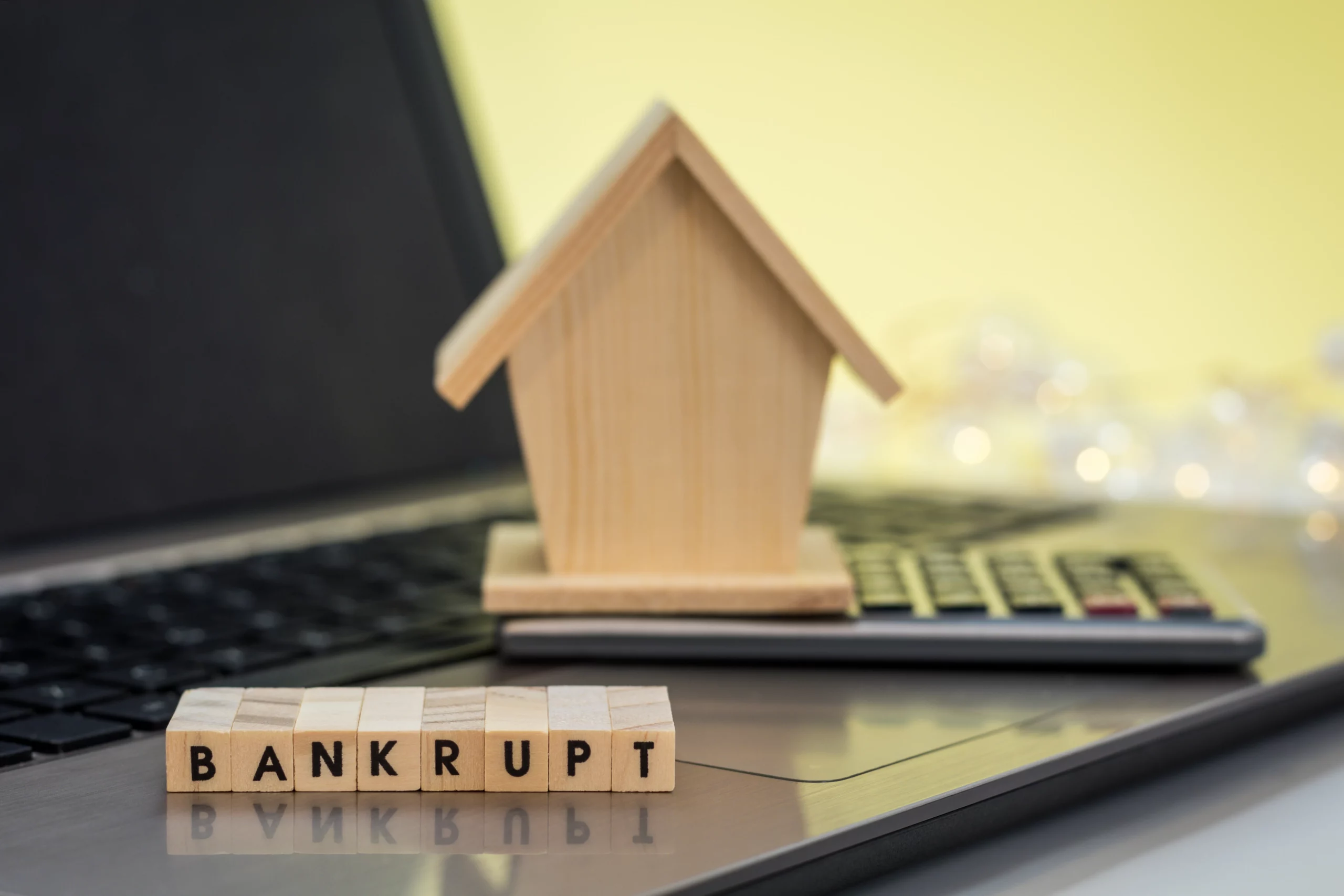 Bankrupt blocks with house and calculator on laptop symbolizing Missouri bankruptcy and home ownership
