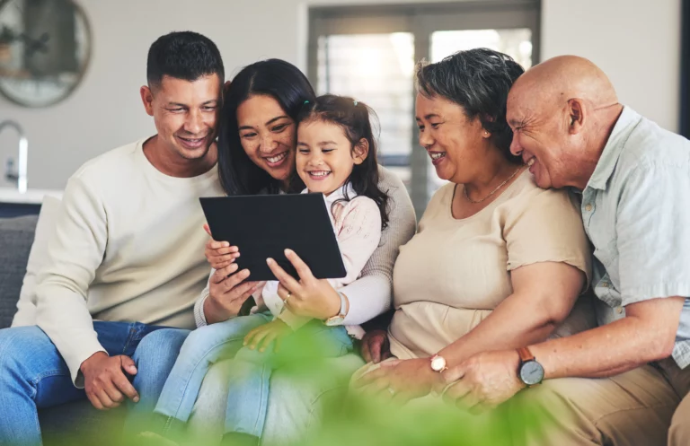 Happy family of five gathered around a tablet on a couch, representing Missouri families planning their future with wills or trusts to protect assets and loved ones