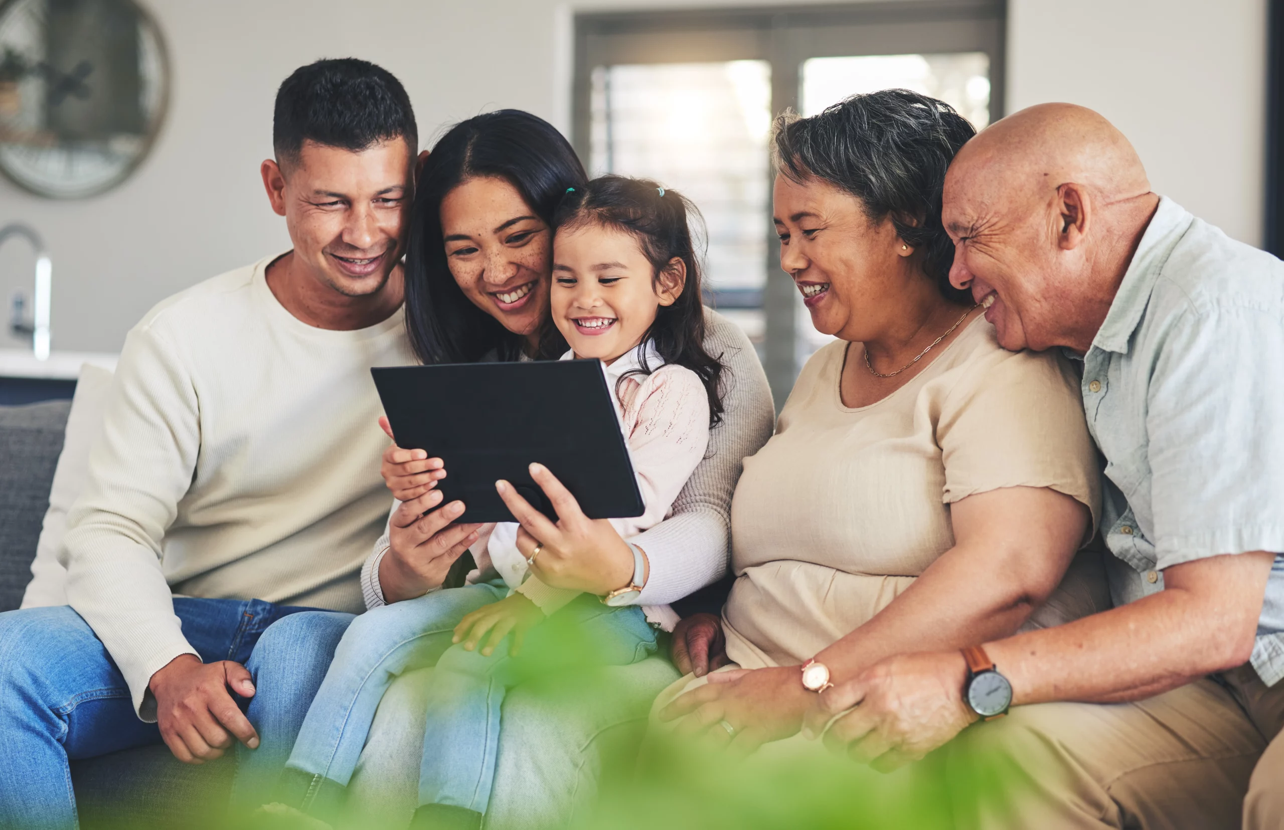 Happy family of five gathered around a tablet on a couch, representing Missouri families planning their future with wills or trusts to protect assets and loved ones