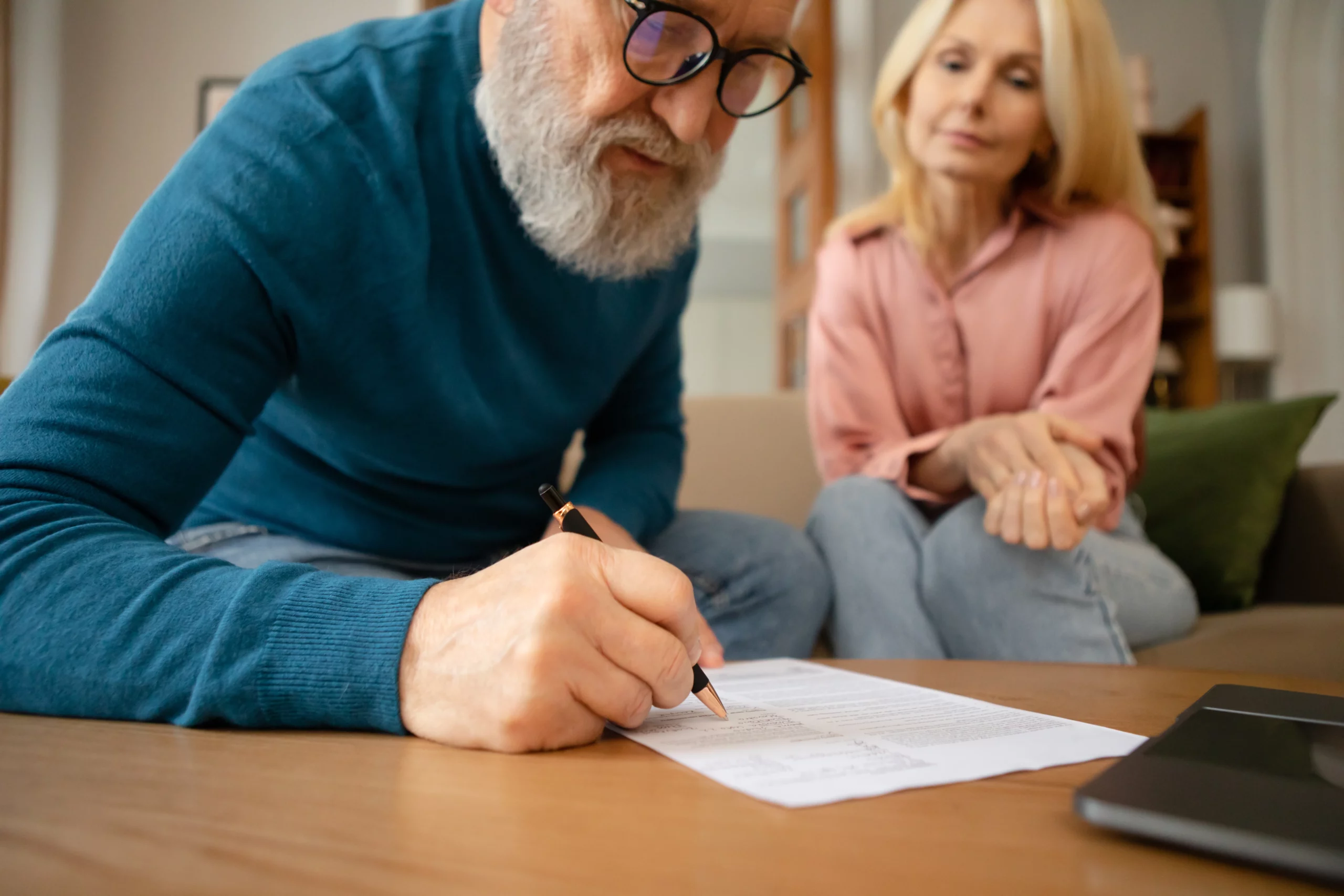 Older man signing legal documents while discussing estate planning with a family member, representing dying without a will in Missouri.